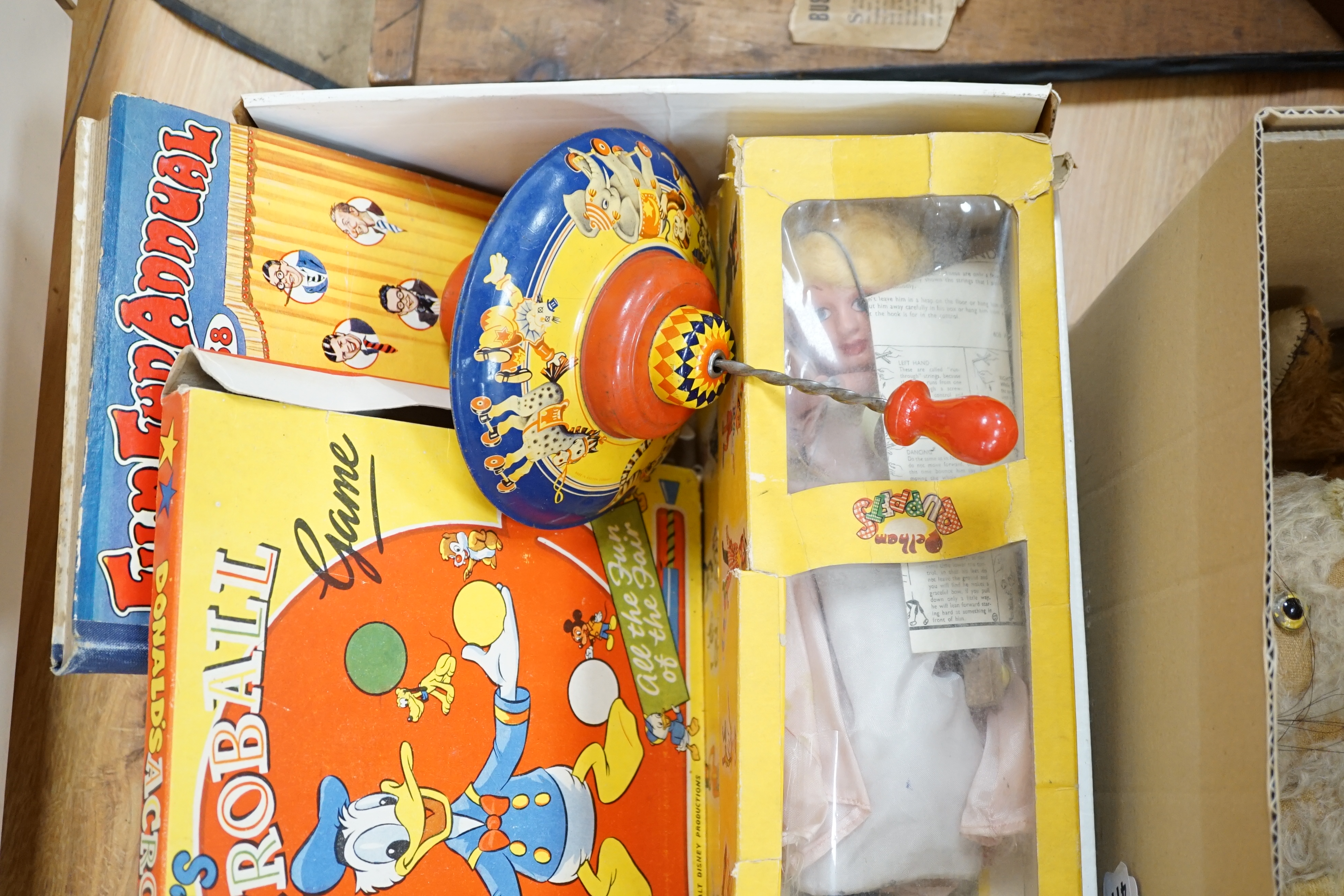 An early 20th century cased Bussey’s Hawk kite, a black walkie talkie doll, a four slot money box, an early Pelham puppet and two others, a hump backed teddy, together with various games and soft toys